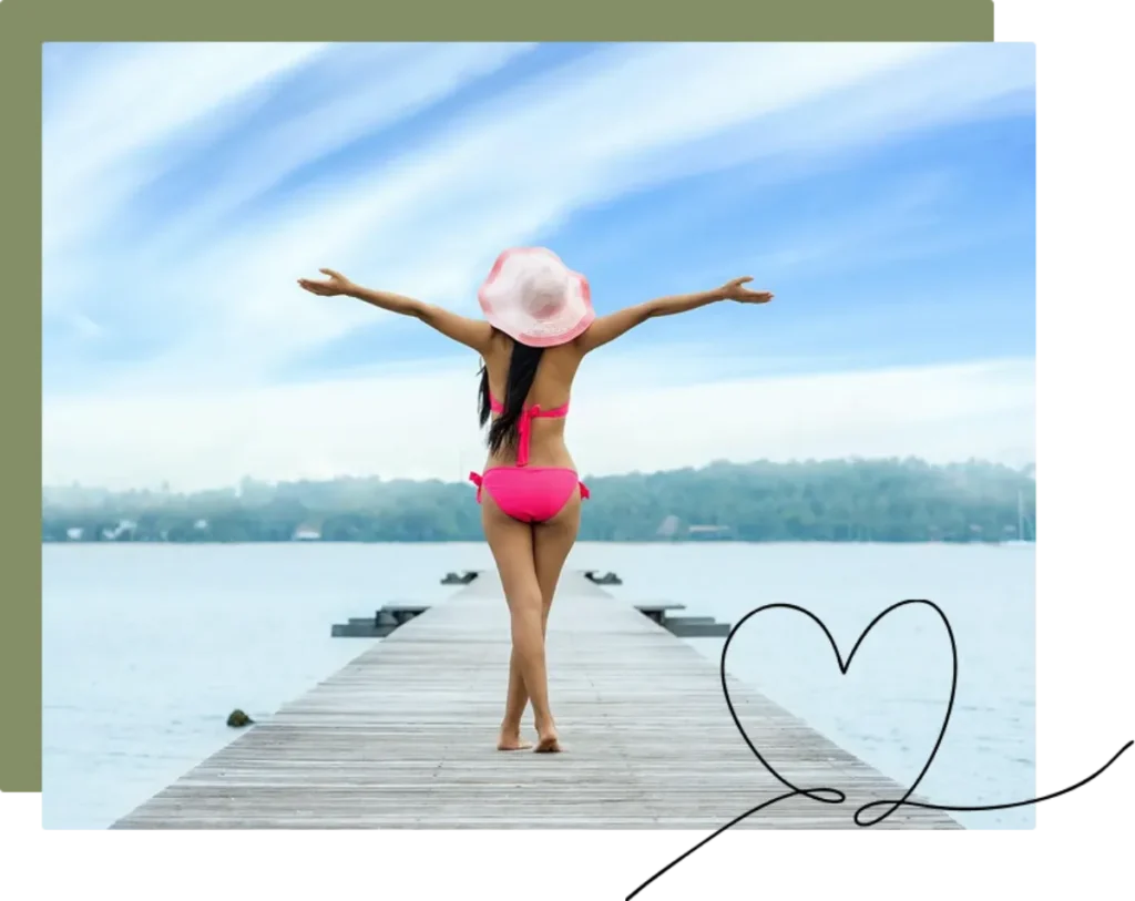 a woman stands at the end of a pier with her arms outstretched after finding a women’s health and wellness solution