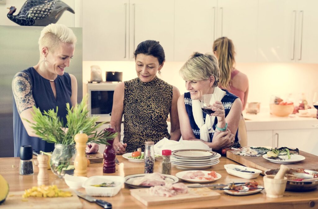 Women preparing food together in a kitchen as part of a supportive, sustainable nutrition routine.